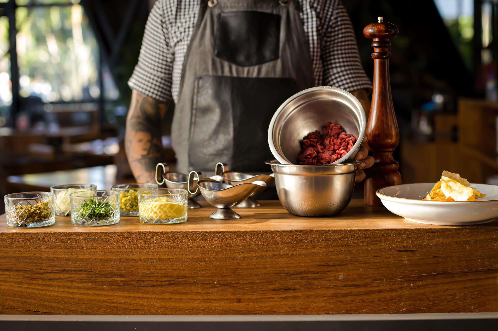 A small professional kitchen counter with utensils and herbs